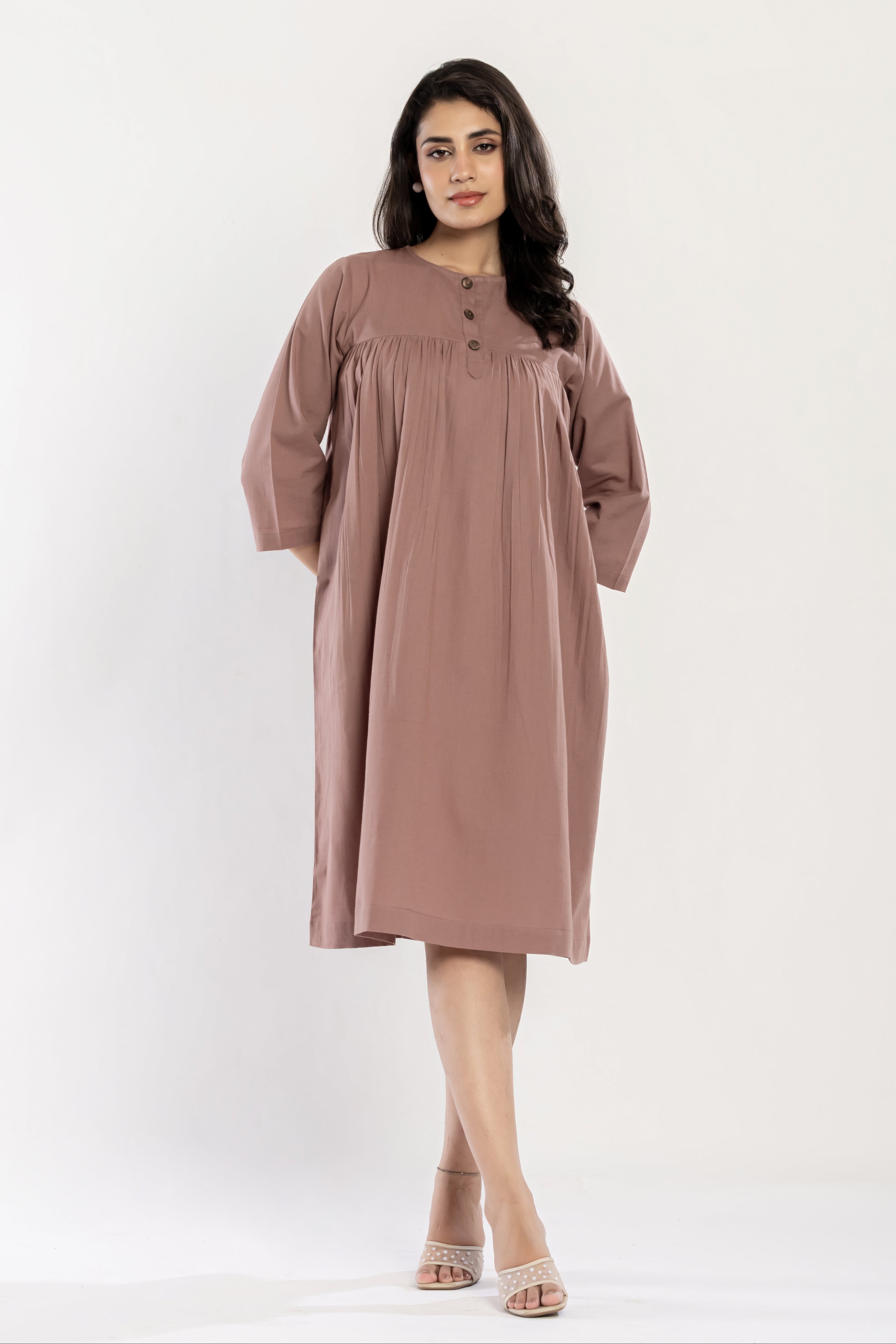 Woman wearing a long, light brown dress on a white background