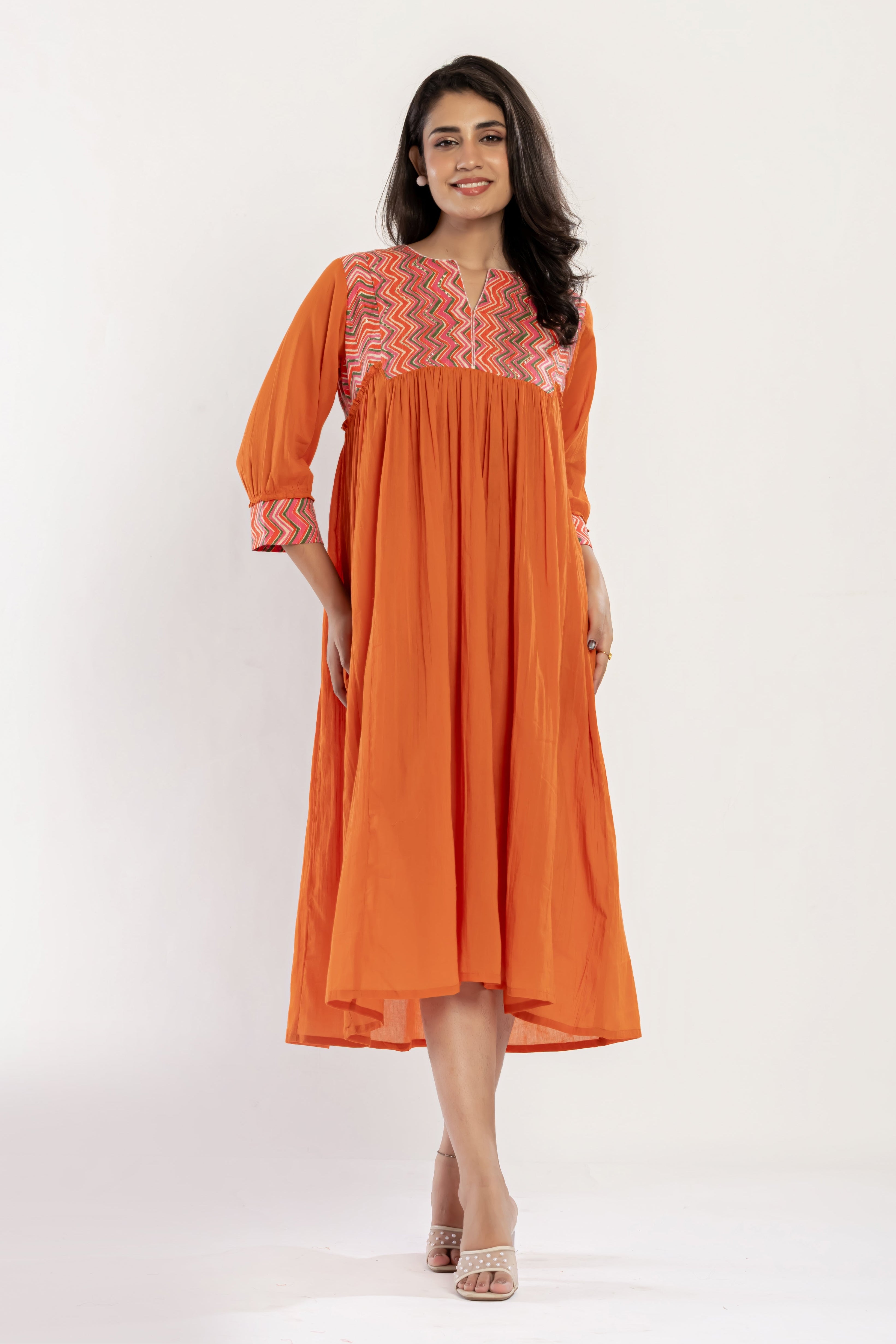 Woman wearing an orange dress with embroidery on a white background