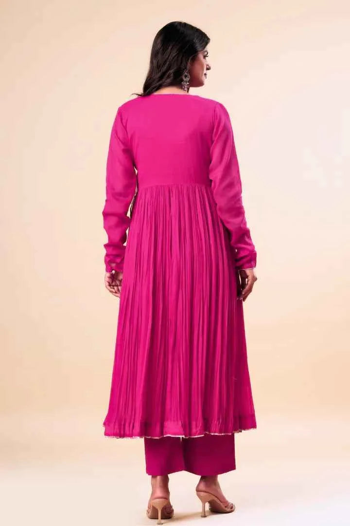 Woman wearing a pink traditional outfit with pleated skirt on a beige background