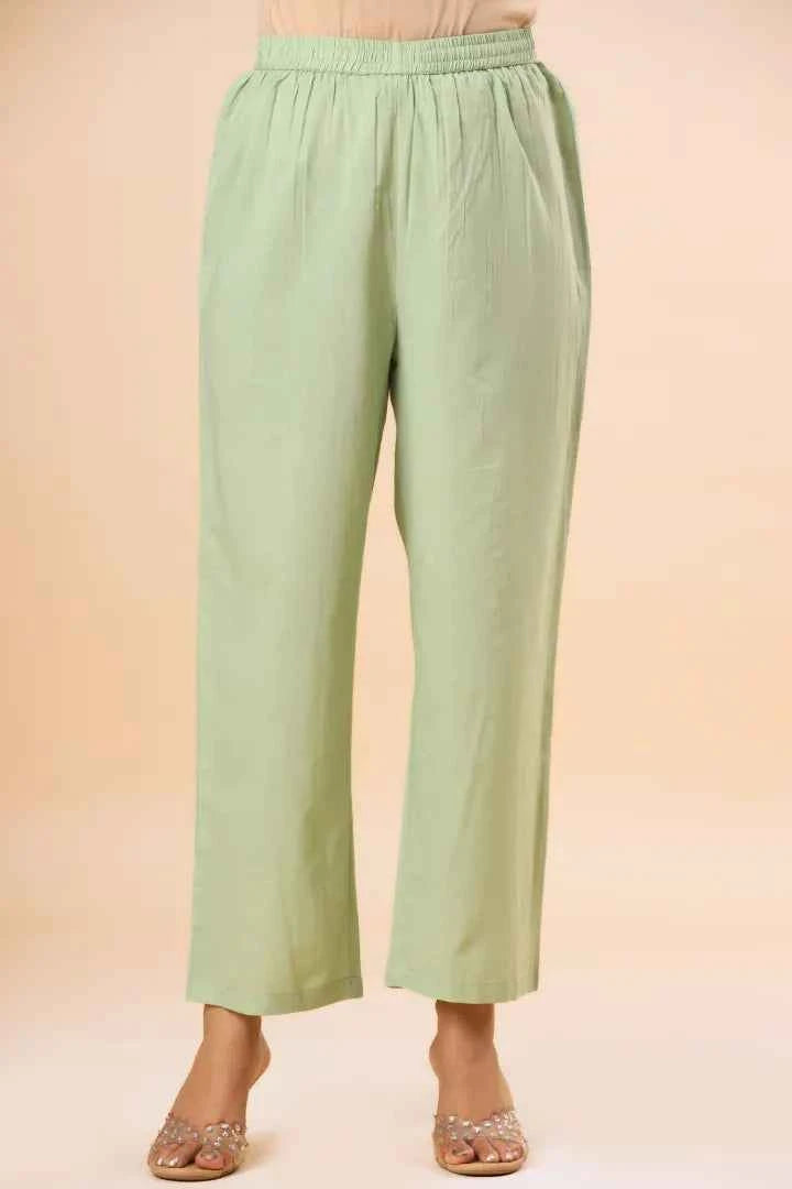 Light green pants worn by a person on a beige background