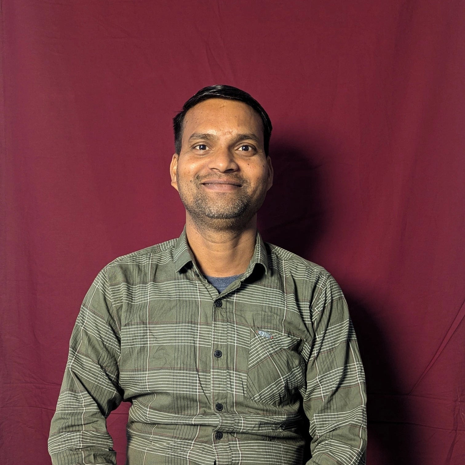Man wearing a green checkered shirt against a red background