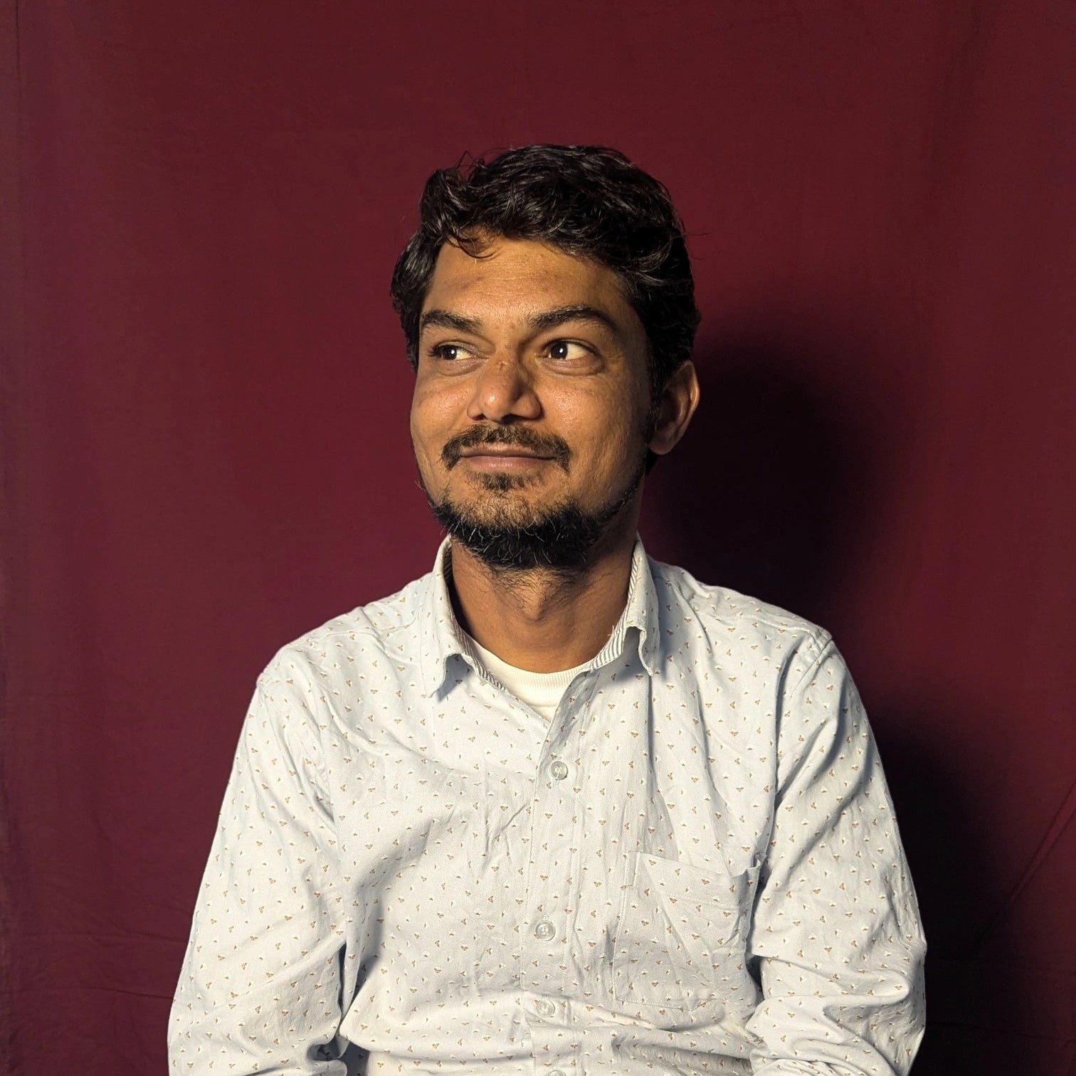 Man wearing a light-colored shirt against a dark red background