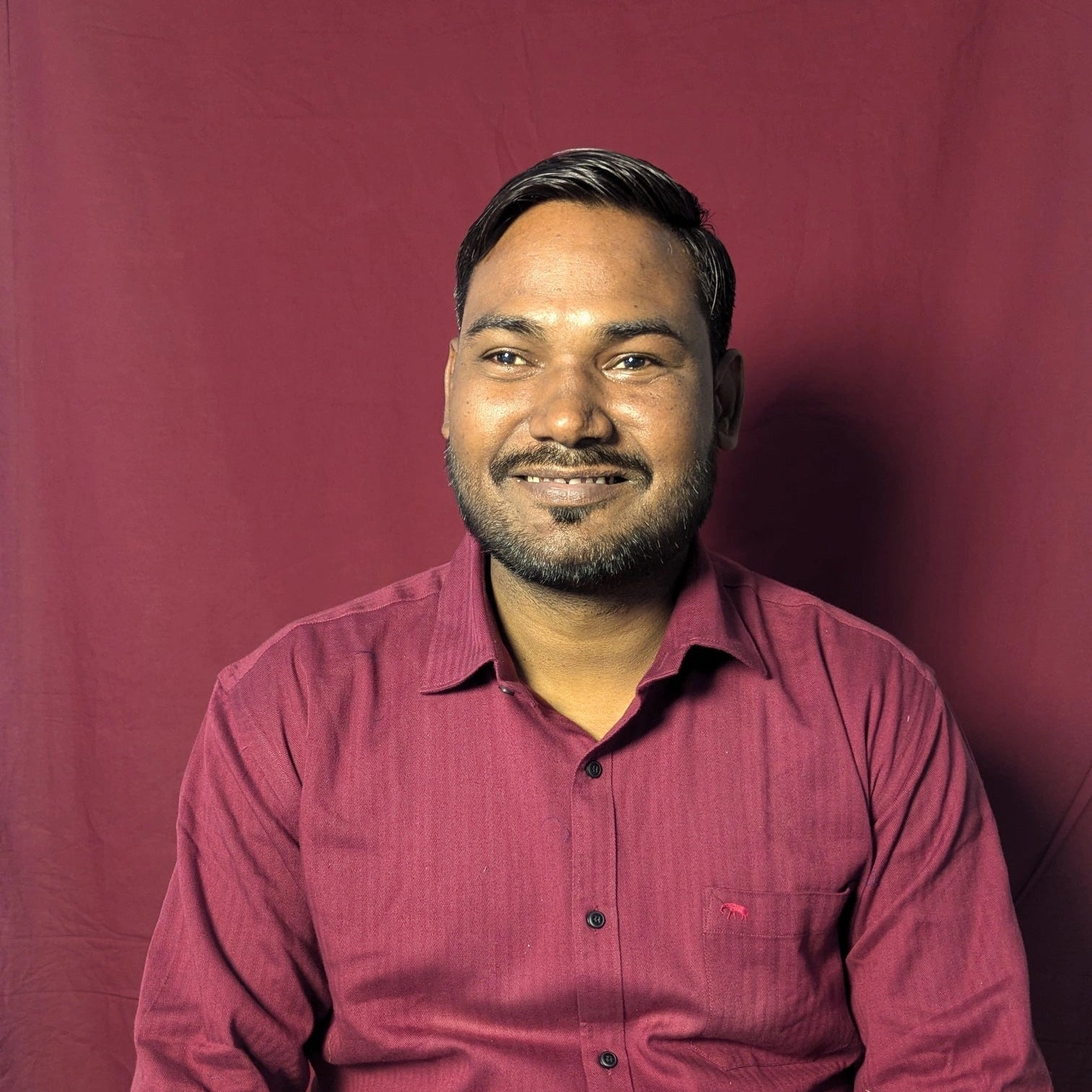 Man wearing a red shirt sitting against a red background