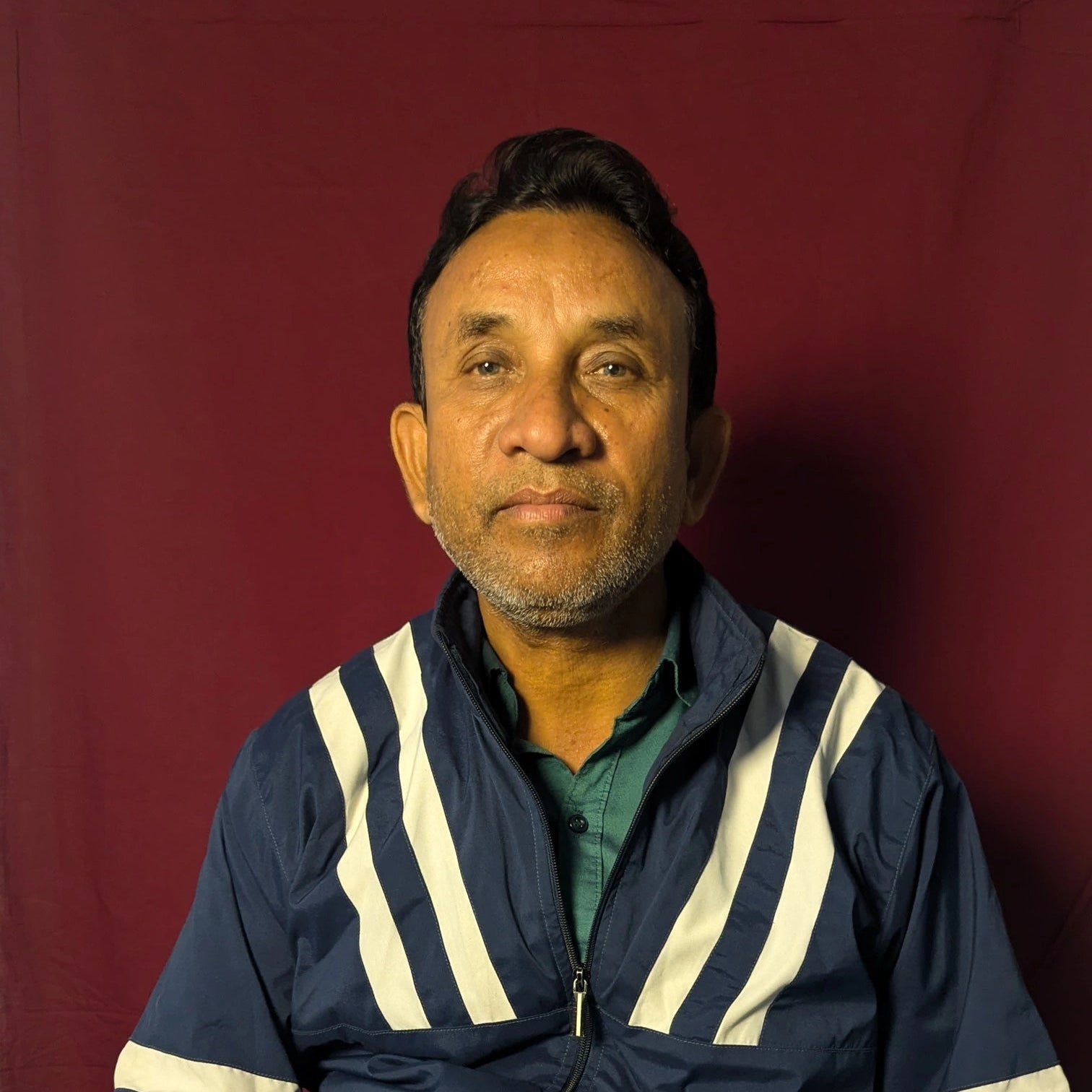 Man wearing a blue jacket with white stripes against a red background