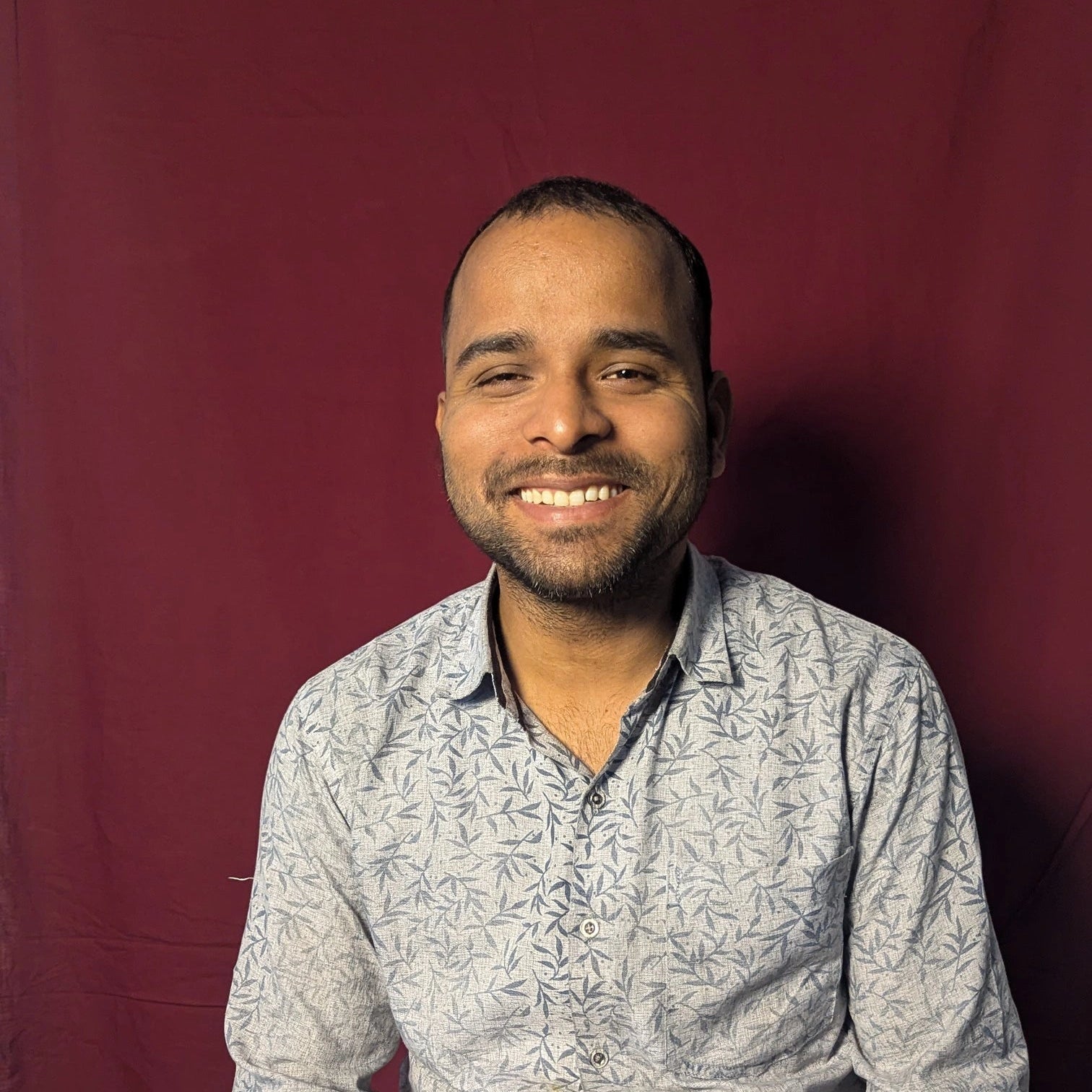 Man wearing a patterned shirt against a red background