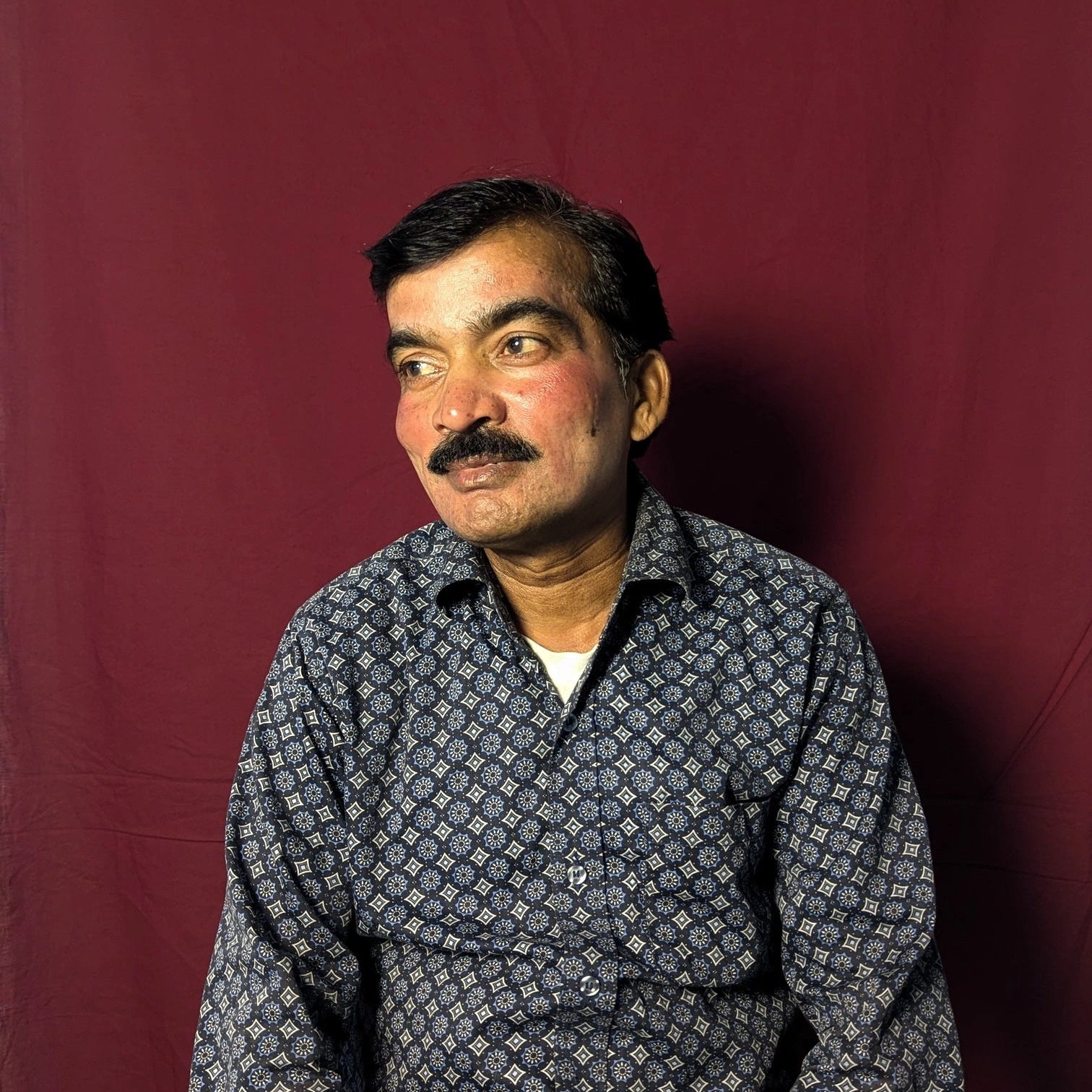 Man wearing a patterned shirt against a red background