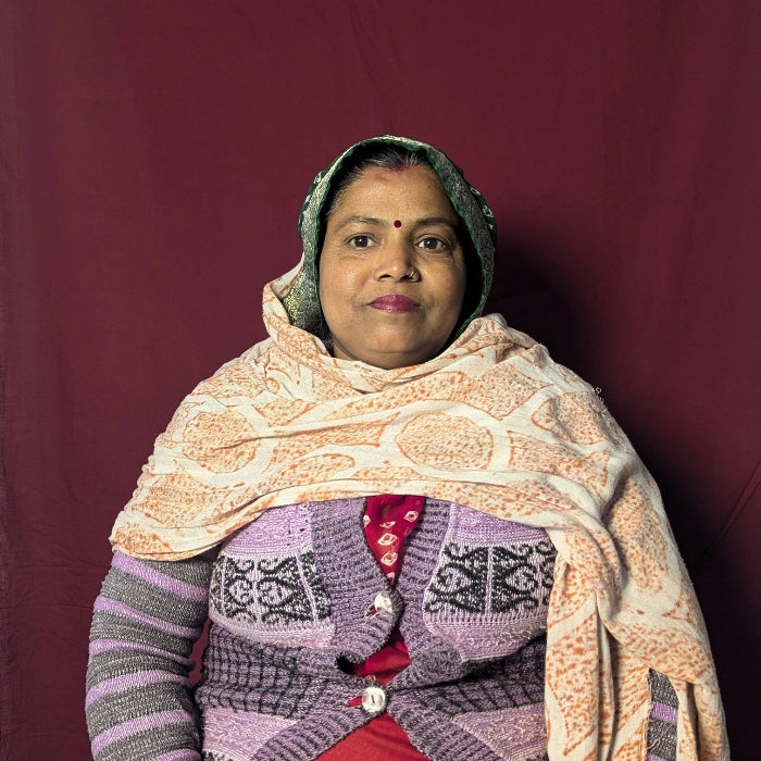 Woman wearing a patterned shawl and sweater against a maroon background