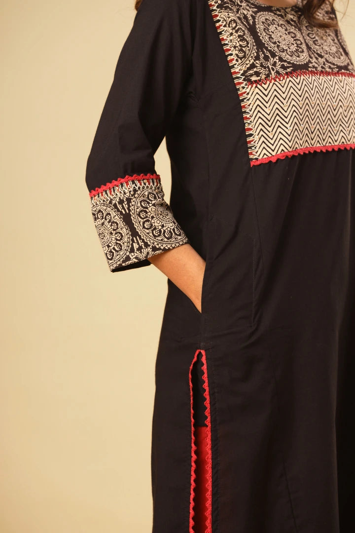 Black dress with intricate patterns and red accents on a beige background