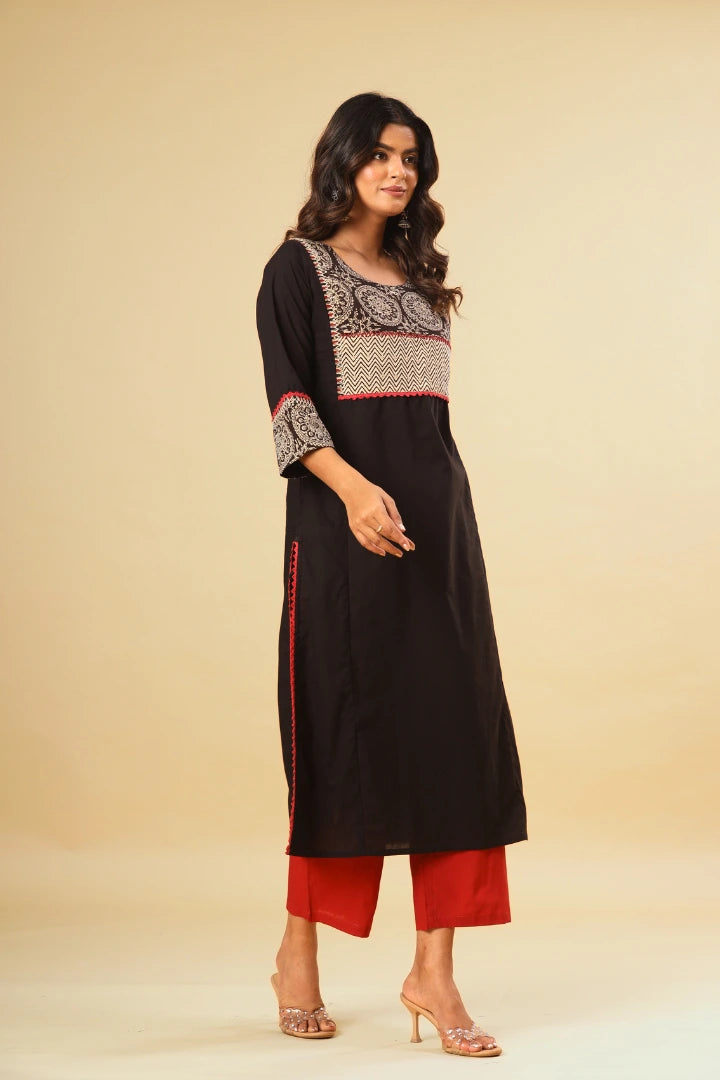 Woman wearing a black kurta with red pants on a beige background